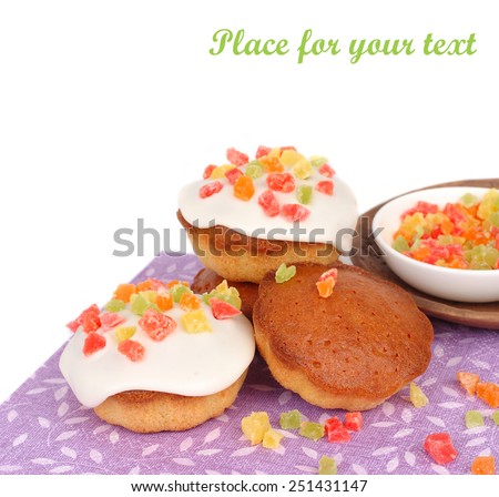 House fragrant biscuits with confectionery mastic and candied fruits on a violet napkin on a white background.