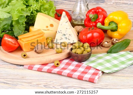 Cheese of various grades, fresh vegetables and olives on a light wooden background. Ingredients for preparation of the Italian vegetarian pizza.