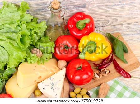 Cheese of various grades, fresh vegetables and olives on a light wooden background. Ingredients for preparation of the Italian vegetarian pizza. Top view.