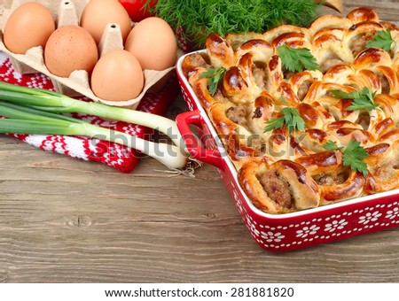 Meat pie and ingredients for preparation of pie on a wooden background.