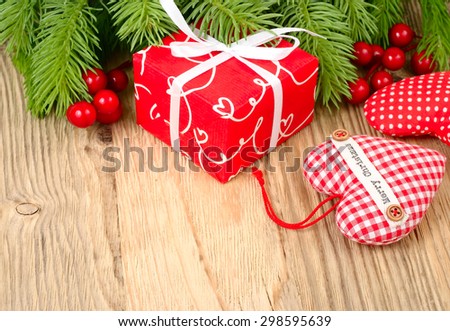 Red gift box, red berries and red checkered textile heart on a wooden background. A Christmas background with a place for the text.