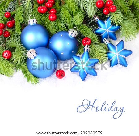 Blue Christmas balls and stars and red berries on fluffy branches of a Christmas tree on a white background. A Christmas background with a place for the text.