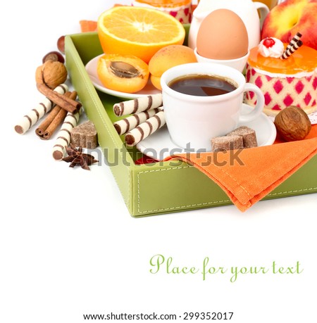 Breakfast for every taste in a tray: coffee, fruit, juice, boiled egg, cakes and wafer tubules on a white background with a place for the text.
