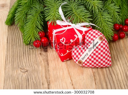 Red gift box and red checkered heart on branches of a Christmas tree on a wooden background. A Christmas background with a place for the text.