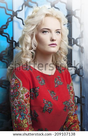 Portrait of a beautiful young blonde woman with a stern look. Outdoors shot.