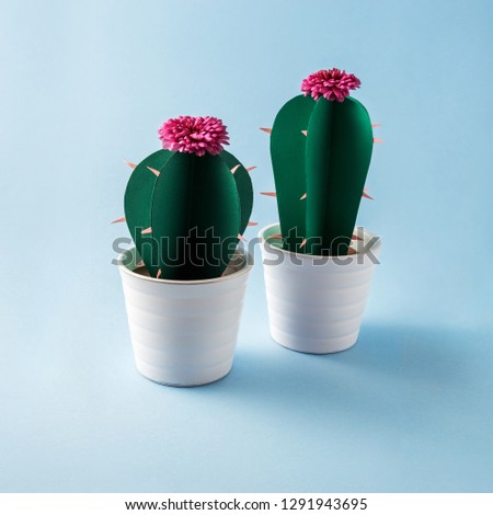 Creative concept photo of paper cactus flowers in pots on blue background.