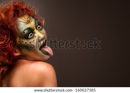 A portrait of a girl with ugly halloween frog or toad tattoo painted on her face as a mask.