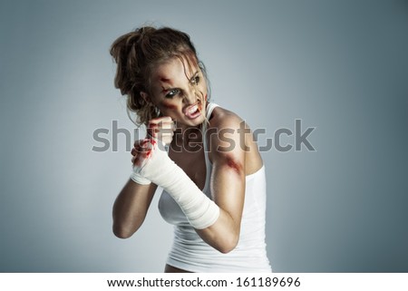 A Photo Of Woman Standing In Fight Position With Blood Over The Face And Fists.