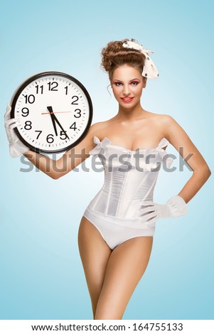 A Cute Pin-Up Girl With A Vintage Hairstyle Holding An Office Wall Clock And Showing The Time.