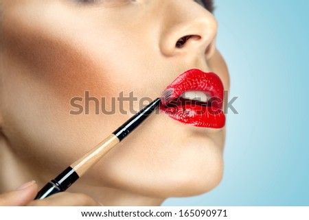 Fashion Photo Of Face Makeup Demonstrating Lips Of A Cute Girl Painted With Bright Lipstick With The Hepl Of Brush.