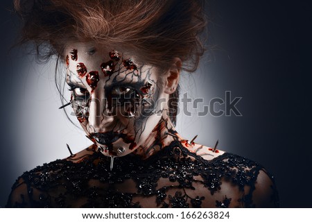 A Girl In A Creepy Halloween Costume Of A Witch With Peircing And Cracked Face Paint Looking With Disguise.