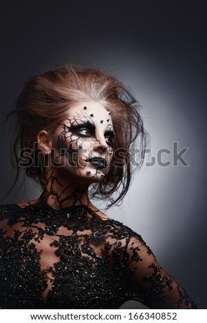 A Girl Posing In A Creepy Halloween Costume Of A Witch With Peircing And Cracked Painted Face.