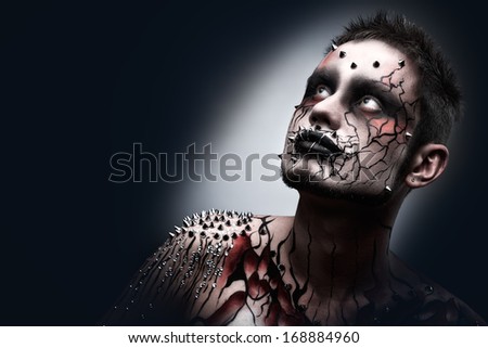 A creepy halloween makeup of a dark thoughtful moor with a peircing and scary body art.
