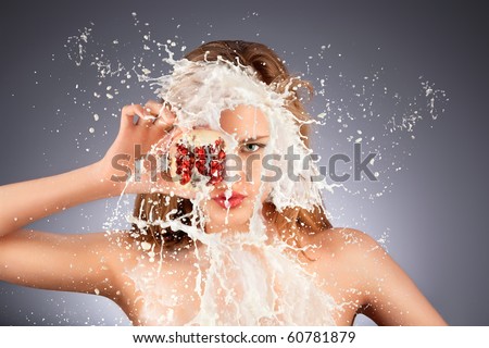 Fruit splash. A portrait of a nude hot model with a pomegranate\'s half in her hand in milky splash.