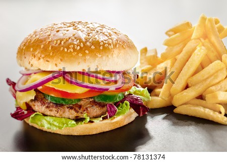 Unbearable desire. A closeup of a tempting tasty burger with red onion and vegs along with yummy french fries.