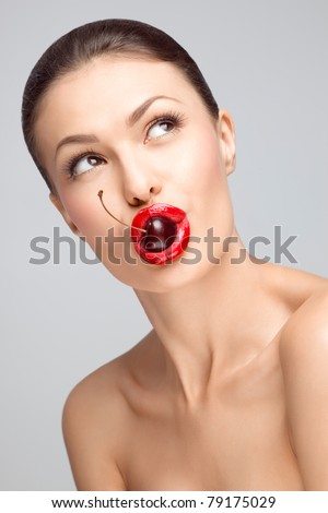 A sexy nude chick holding a juicy cherry in her nude chick