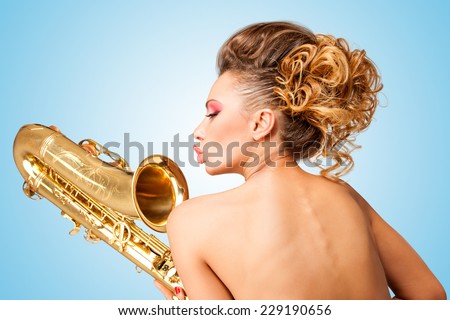 Retro portrait of a nude pin-up girl with vintage winged eyes, turning her back on and holding a saxophone upside down on blue background.