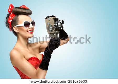 A photo of the pin-up girl in corset and gloves holding vintage 8mm camera.