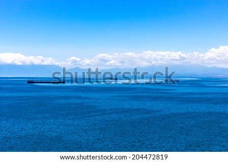 Beautiful seascape of three tanker ships at the blue waters of Aegean sea with mountains and low clouds on the background.The water is breathtaking.Thessaloniki, Greece