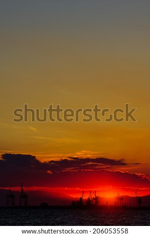 Silhouette of trade harbor at late sunset with mountains in the background