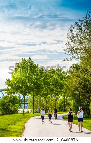 Few women running and cycling in beautiful green park alongside the river.Captured at Danube island,Vienna,Austria