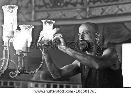 NITEROI, BRAZIL - FEBRUARY 4, 2014: A male worker cleans up a chandelier during its process of restoration. February 4, 2014 in Niteroi, Brazil.
