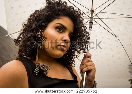 Brazilian model posing in the rain carrying an umbrella