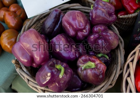A basket full of purple capsicums for sale in a street market