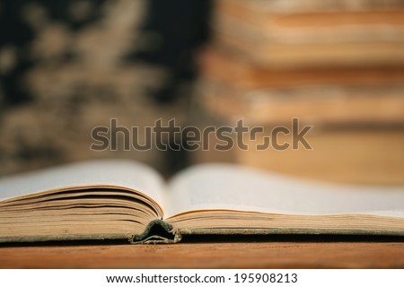 open end of the old book on a wooden boards background on a pile of books