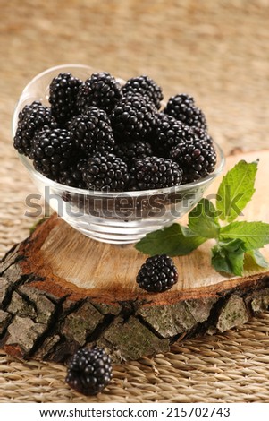 yogurt with blackberries in a glass jar and blackberries on the background of wooden boards