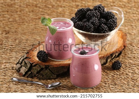 yogurt with blackberries in a glass jar and blackberries on a wicker mat background
