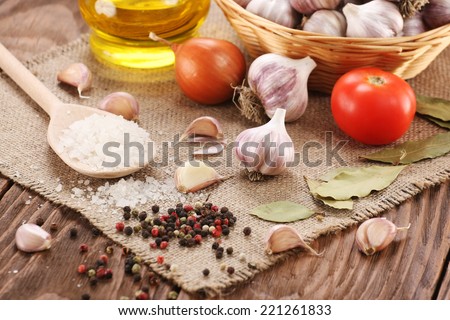 garlic, sea salt, pepper, sunflower oil, bay leaf, onion and tomato on the background burlap and wooden planks