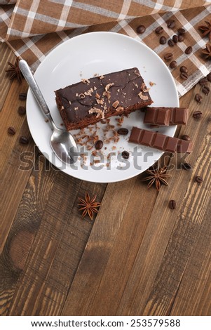 chocolate cake and chocolate in a bowl on a wooden boards background