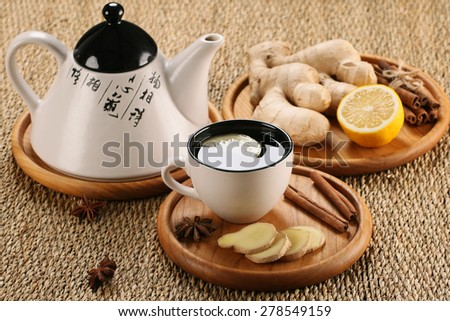 ginger tea in a cup of glass, ginger, lemon, cinnamon, star anise on the background of a mat moven