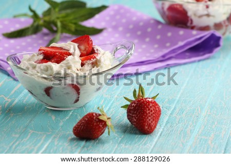 strawberries with cream in a bowl of glass on the background of painted boards