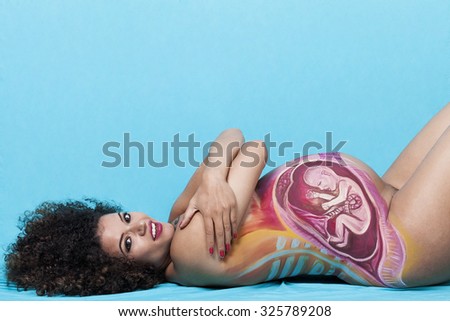 Pregnant woman portrait lying with baby painted on belly