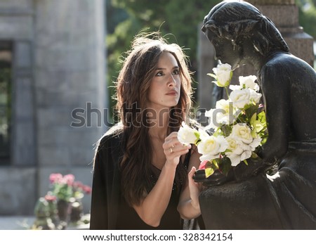 Woman in the graveyard giving flowers to the loved one