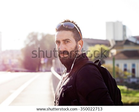 Handsome sportsman portrait in the city wearing earphones and looking