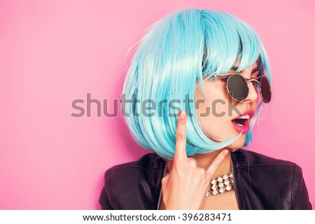Pop girl portrait wearing blue wig and making the horns