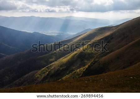 Mountain landscape with Sun behind the clouds producing warm and positive sun rays