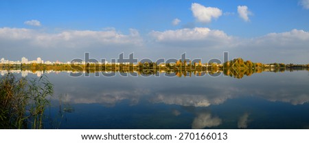 Panoramic city view on the water side with grass and trees and reflections