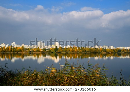 City view on the water side with grass and trees and reflections
