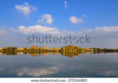 Symmetrical view of autumn trees reflected in the lake with blue sky and colorful trees