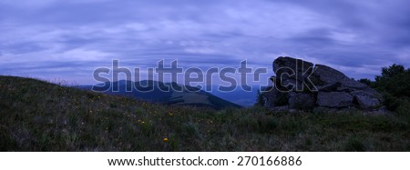 Night mountains landscape with yellow flower meadow hills and slopes and cloudy sky