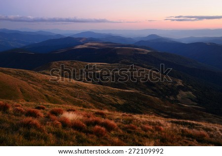 Mountain twilight landscape with purple and pink sky and red autumn grasses