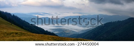 Panoramic sunrise mountains landscape with foggy valleys and forests and pink clouds