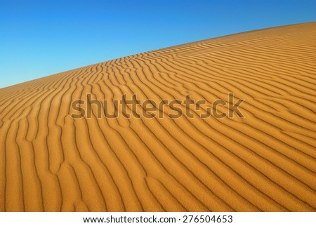 Yellow soft sand dunes in desert with sand patterns and lines and shadows