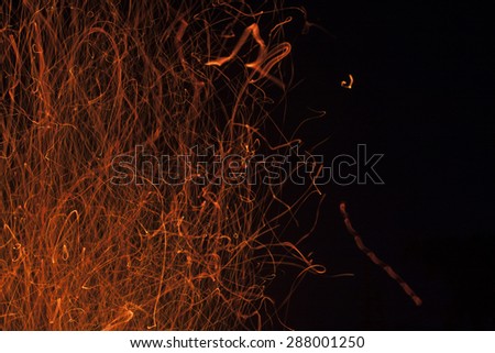 The dancing sparks from a fire on a black background.