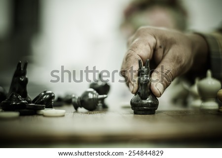 Male hand holding chess pawn, about to begin the game