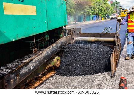industrial pavement truck laying fresh asphalt on construction site